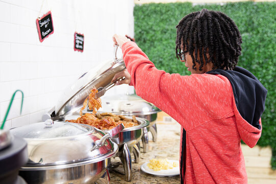 Teen getting food from a hotel continental breakfast.