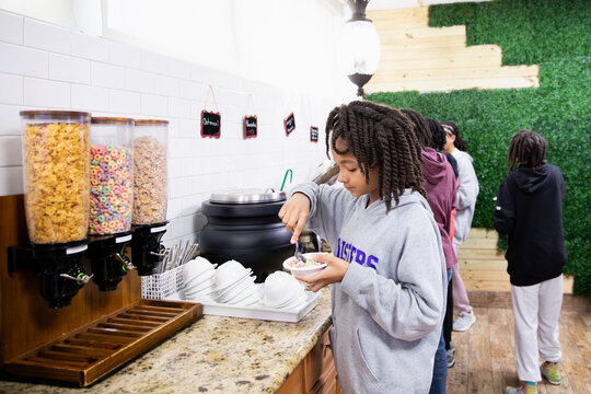 Child getting food from a hotel continental breakfast.