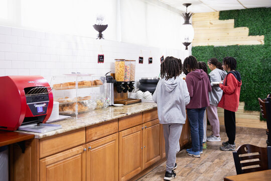 Children getting food from a hotel continental breakfast.