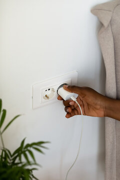 Woman Putting Plug Into Socket 