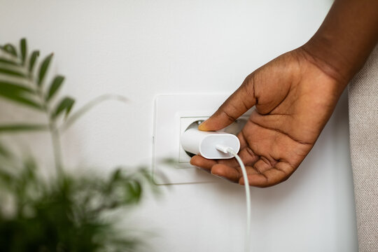 Woman Putting Plug Into Socket 
