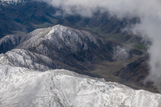 Aerial view of snow capped Mountain ranges  though the clouds