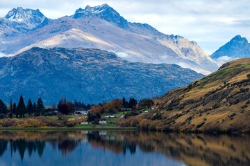Houses surrounded by mountains reflected in a lake