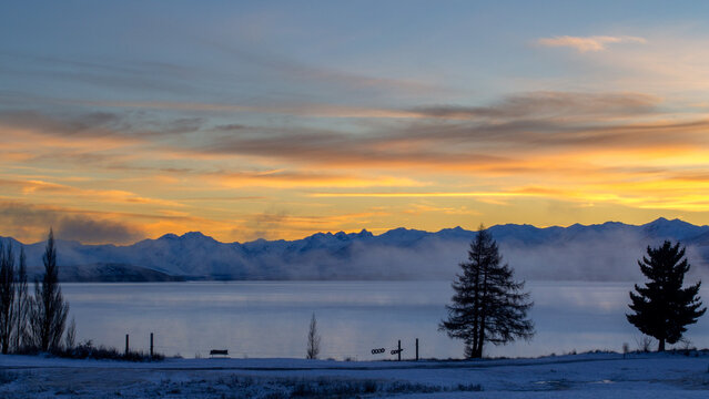 Sunrise with an fiery sky offset by the cool icy mist of the lake
