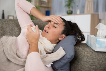 ill woman with tissues holds her forehead