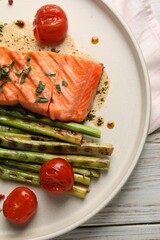 Tasty grilled salmon with tomatoes, asparagus and spices on plate, top view