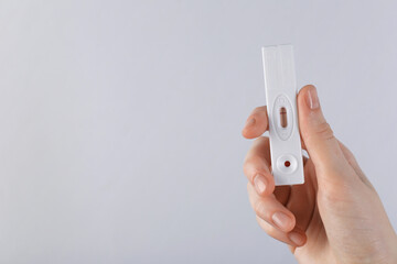 Woman holding disposable express test on light background, closeup. Space for text