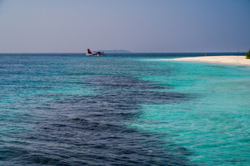 Nice sea coast with a sandy beach and a seaplane on the surface.