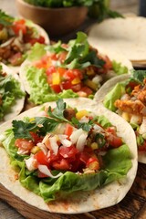 Delicious tacos with vegetables and meat on table, closeup