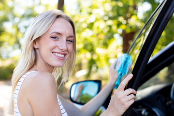 young woman cleaning car with microfiber cloth