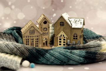 A knitted scarf surrounds toy houses. The houses and scarf symbolize warmth and comfort in autumn...