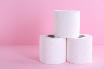 Soft toilet paper rolls on pink background, closeup. Space for text