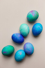 Blue and green dyed Easter eggs against pink backdrop