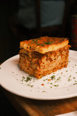 Pastitsio on a white plate with Greek spices