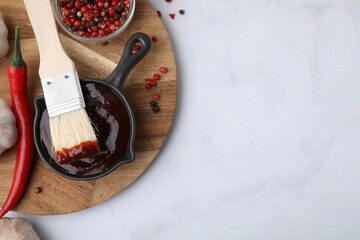 Marinade in gravy boat, ingredients and basting brush on white marble table, flat lay. Space for...