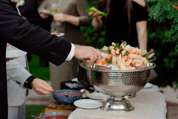 guests wearing suits at reception reaching for shrimp appetizers