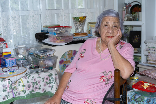 Thoughtful Elderly Lady with Gray Hair Sitting In Living Room.