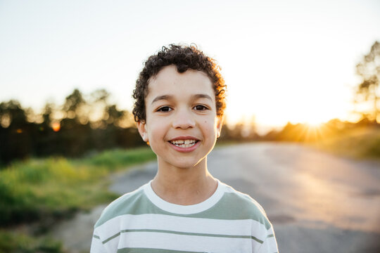 Portrait of cute curly haired boy having fun outside.