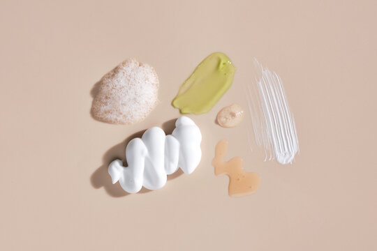 Colored cosmetic smears on pastel beige background top view.