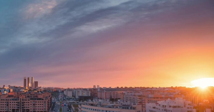Timelapse skyline of modern european city Madrid during sunset with golden light and red clouds during blue hour zoom in day to night time lapse copy space rule of thirds