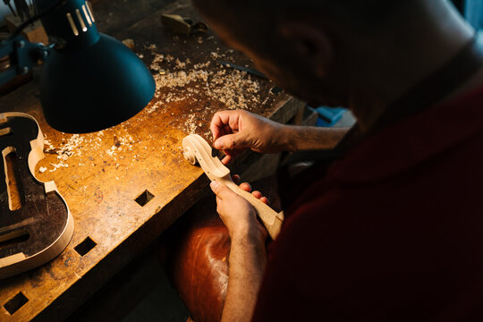 Unrecognizable luthier creating scroll in workshop
