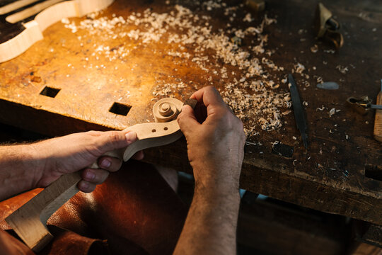 Anonymous master making scroll for violin at table