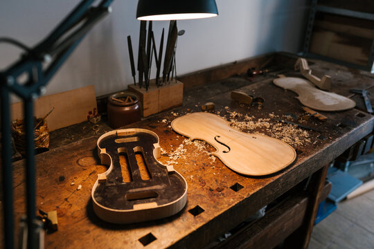 Parts of violin on wooden table in workplace