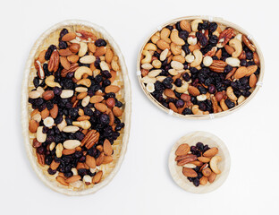 set of three of wooden bowls with mixed nuts on white table