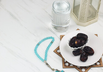 Kurma dan Air Putih, Dates fruit and water on marble white background. Breakfasting concept in Ramadan month. Islamic template for text background. 