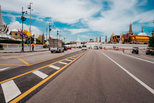 A wide road in Bangkok with traffic and temple roofs