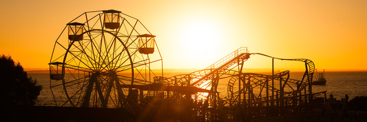 Silhouette of the giant Ferris Wheel in Adventure Island Fun Park silhouetted against setting sun at sunset