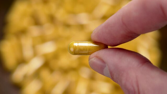Curcuma herbal medicine pill in hand. Yellow medicinal capsule with turmeric powder close up. Selective focus