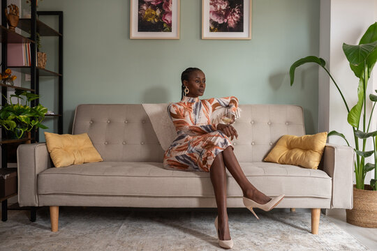 Self assured black woman relaxing with wine in lounge