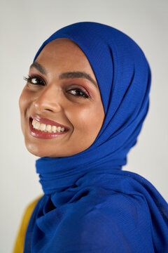 Studio portrait of woman smiling in blue headscarf on white background