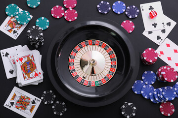 Roulette wheel, playing cards and chips on table, flat lay. Casino game