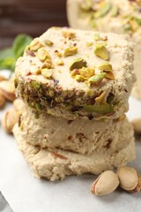 Pieces of tasty halva with pistachios on table, closeup