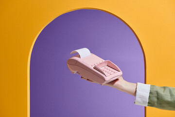 Hand holding a POS terminal with printed receipt on purple