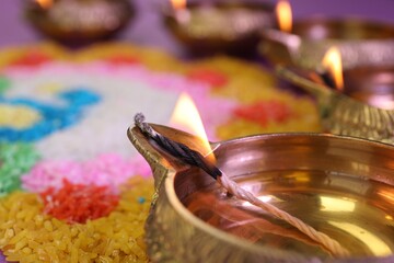 Diwali celebration. Diya lamps and colorful rangoli on blurred background, closeup