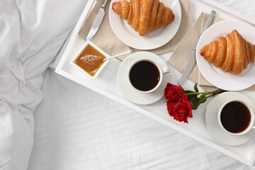Tasty breakfast served in bed. Fresh croissants, coffee and honey on tray, top view. Space for text