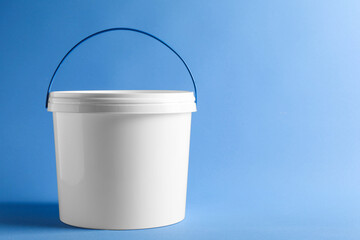 One plastic bucket with lid on light blue background. Space for text © New Africa