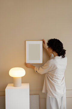 Young woman in stylish, modern room with mockup frame  
