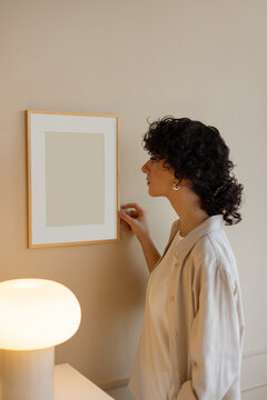 Young woman in stylish, modern room with mockup frame  