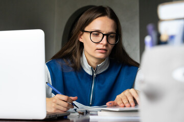Focused college school girl preparing for test exam books, writes note