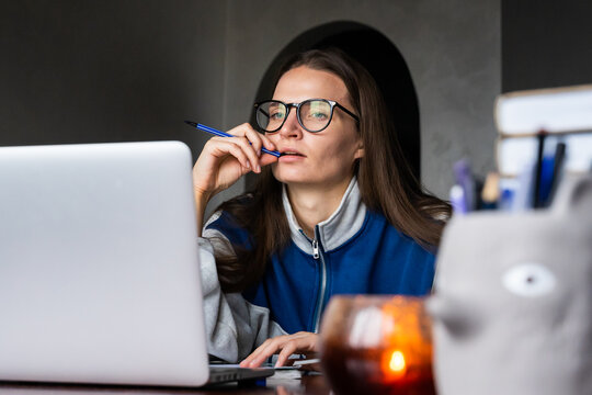woman multitasks, taking notes attending online class on laptop