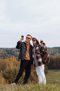 Autumn millennial hiking couple taking selfie on forest hilltop. 