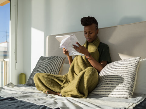 Focused black lady learning language on comfortable bed