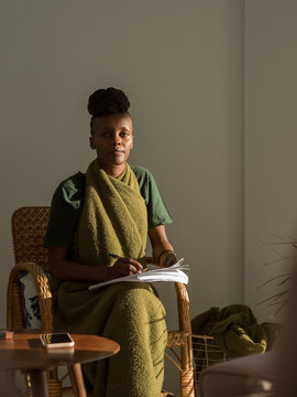Black female linguist sitting on chair with notebook