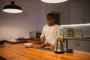 Black woman cutting strawberries for smoothie