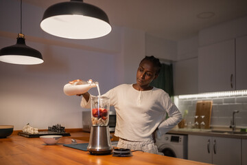 Black woman pouring milk into blender