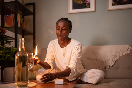 Black woman lighting candle on coffee table